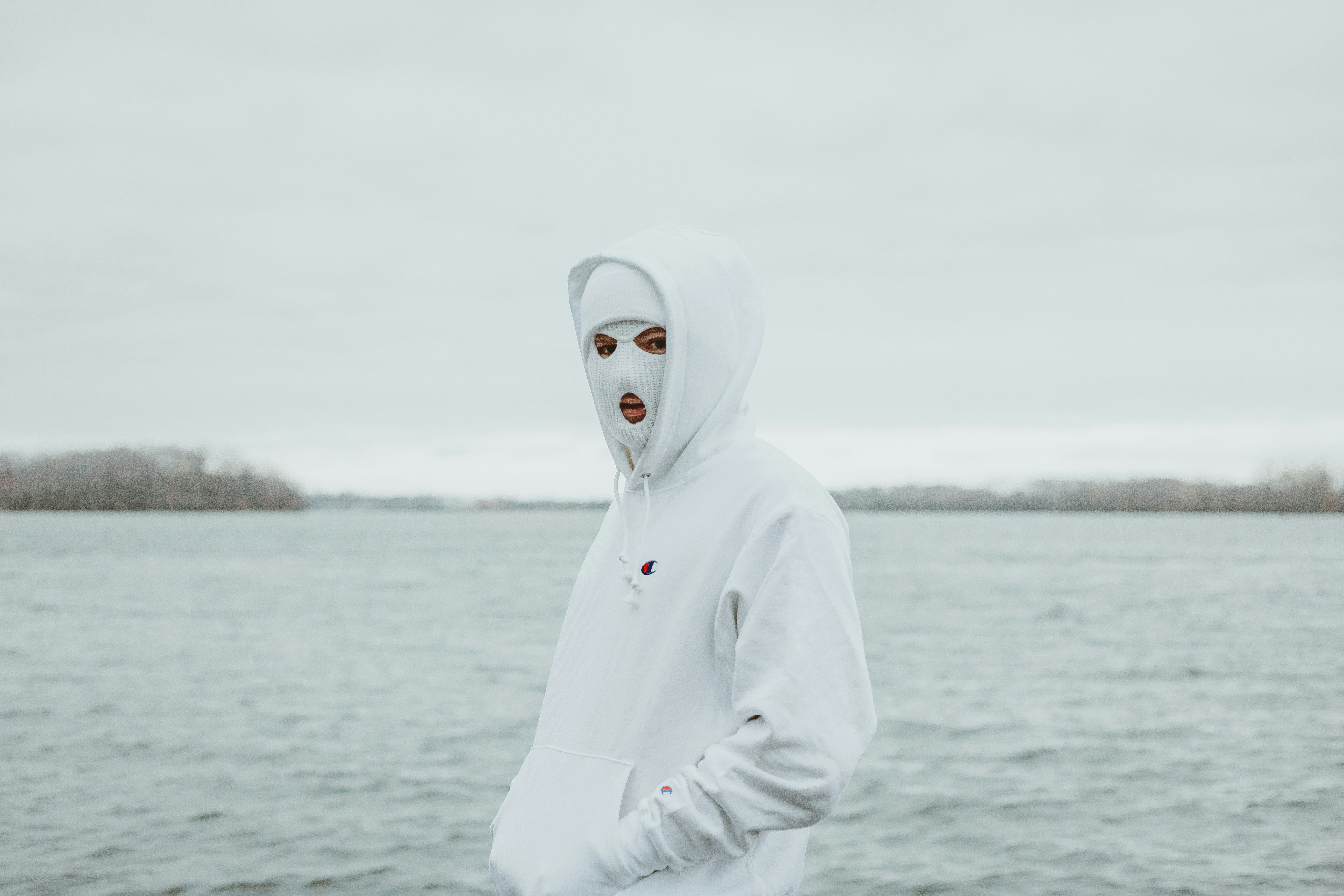 person in white hoodie standing near body of water during daytime